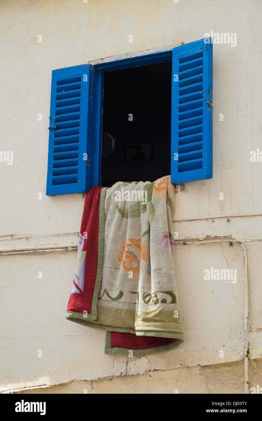 Una finestra con persiane con biancheria da letto messo in onda a Tangeri la medina (città vecchia), il Marocco. Foto Stock
