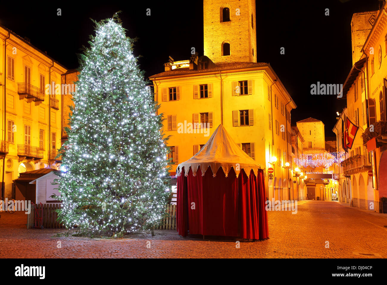 Grande Natale albero illuminato sulla piazza della città davanti di antiche torri presso il centro storico di Alba, Italia settentrionale. Foto Stock