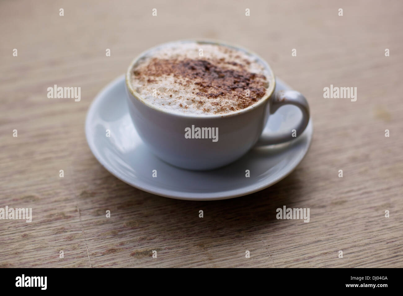 Cappuccino in tazza cinese sulla piastra su una tavola di legno Foto Stock