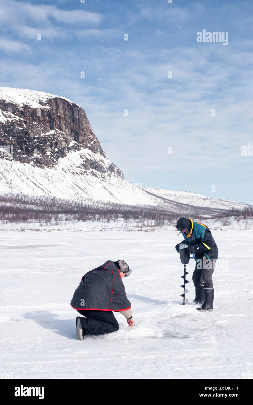 Due uomini Sami pesca sul ghiaccio nel deserto artico, Kiruna, Svezia Foto Stock