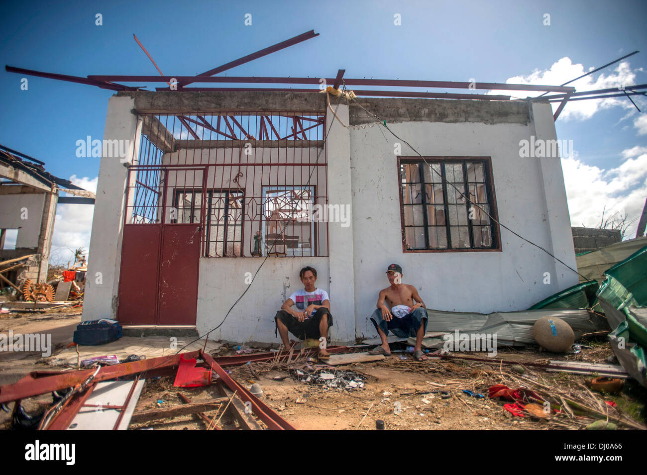 Sit residenti al di fuori della loro casa distrutta all indomani della Super Typhoon Haiyan Novembre 15, 2013 in Guiuan, Filippine. Foto Stock