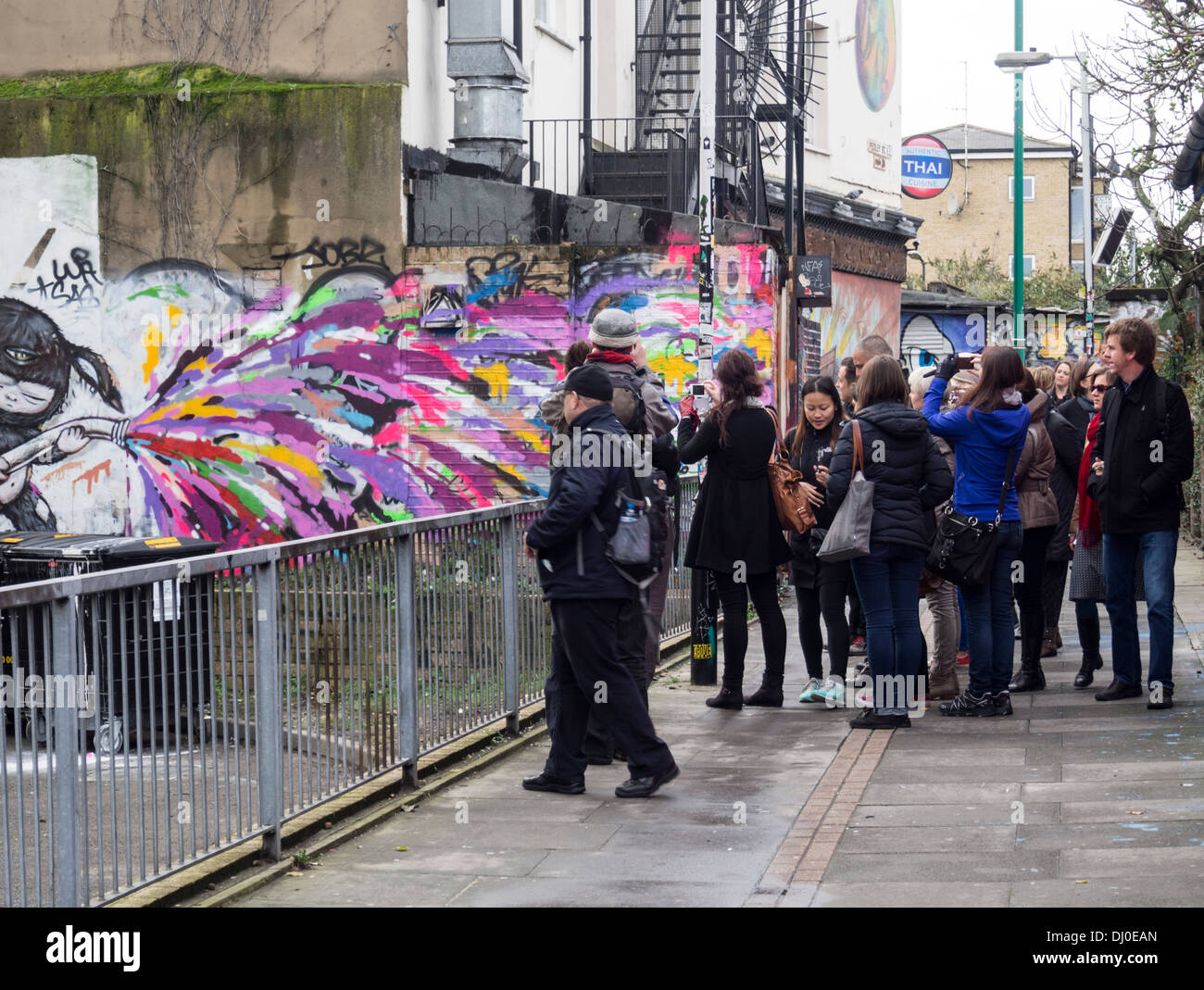 Un gruppo di turisti che frequentano un tour della street art e graffiti in east end di Londra Foto Stock