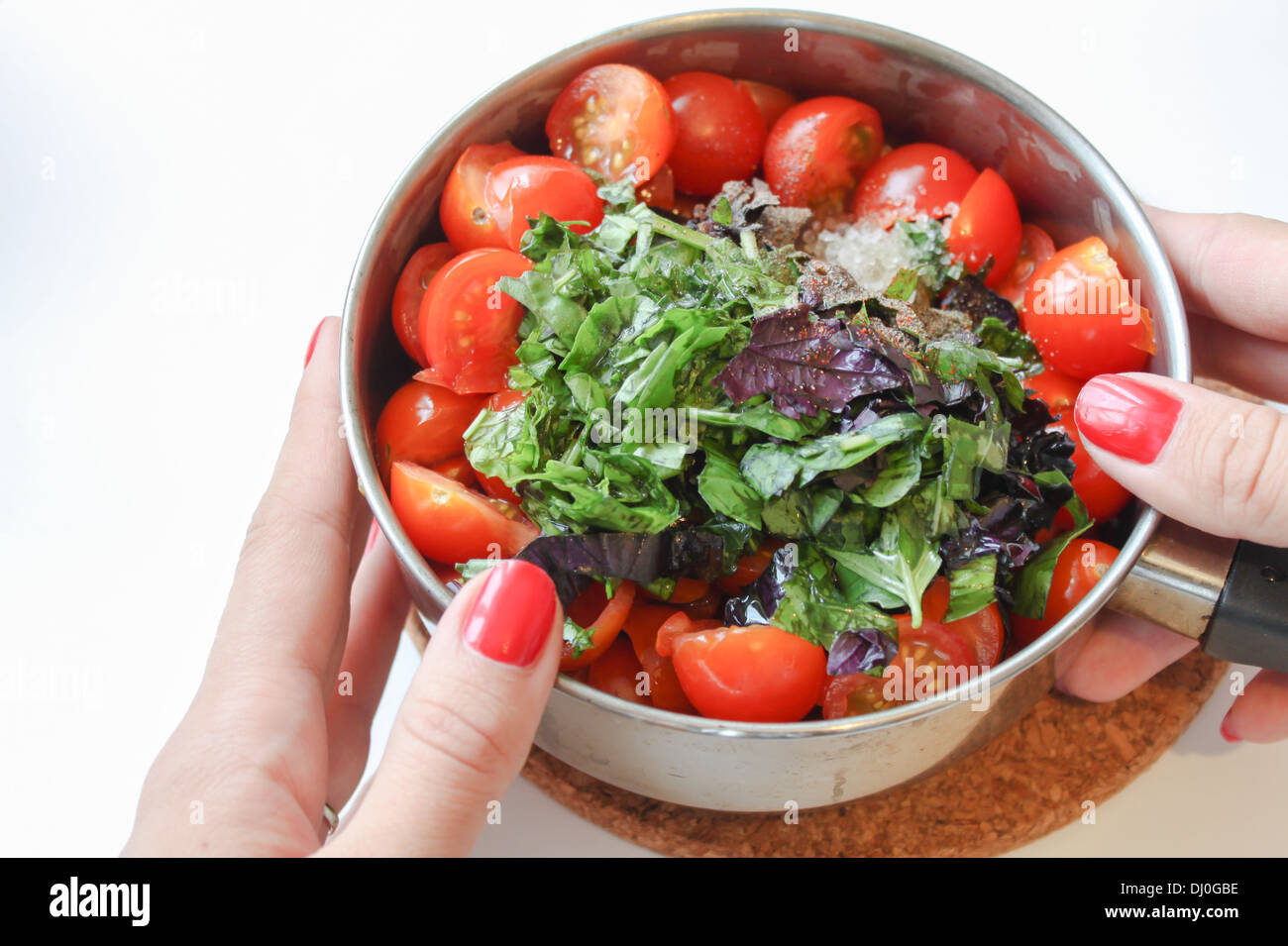 Mani tenendo la pentola con gli ingredienti per cucinare [salsa di pomodoro] [ricetta salsa] su sfondo bianco Foto Stock