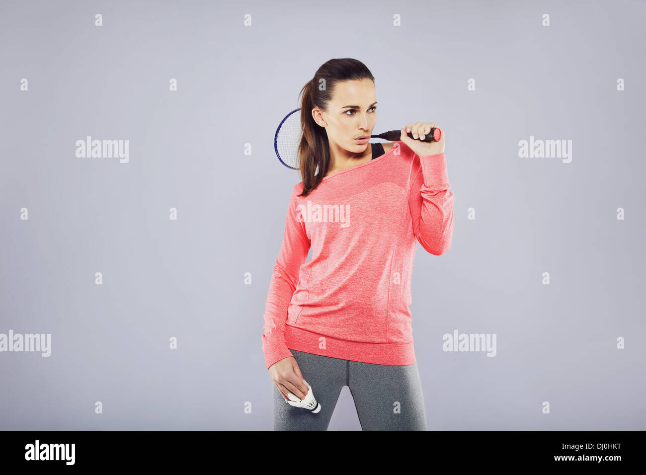 Montare Pretty Woman holding badminton racchetta guardando copyspace mentre in piedi su sfondo grigio Foto Stock