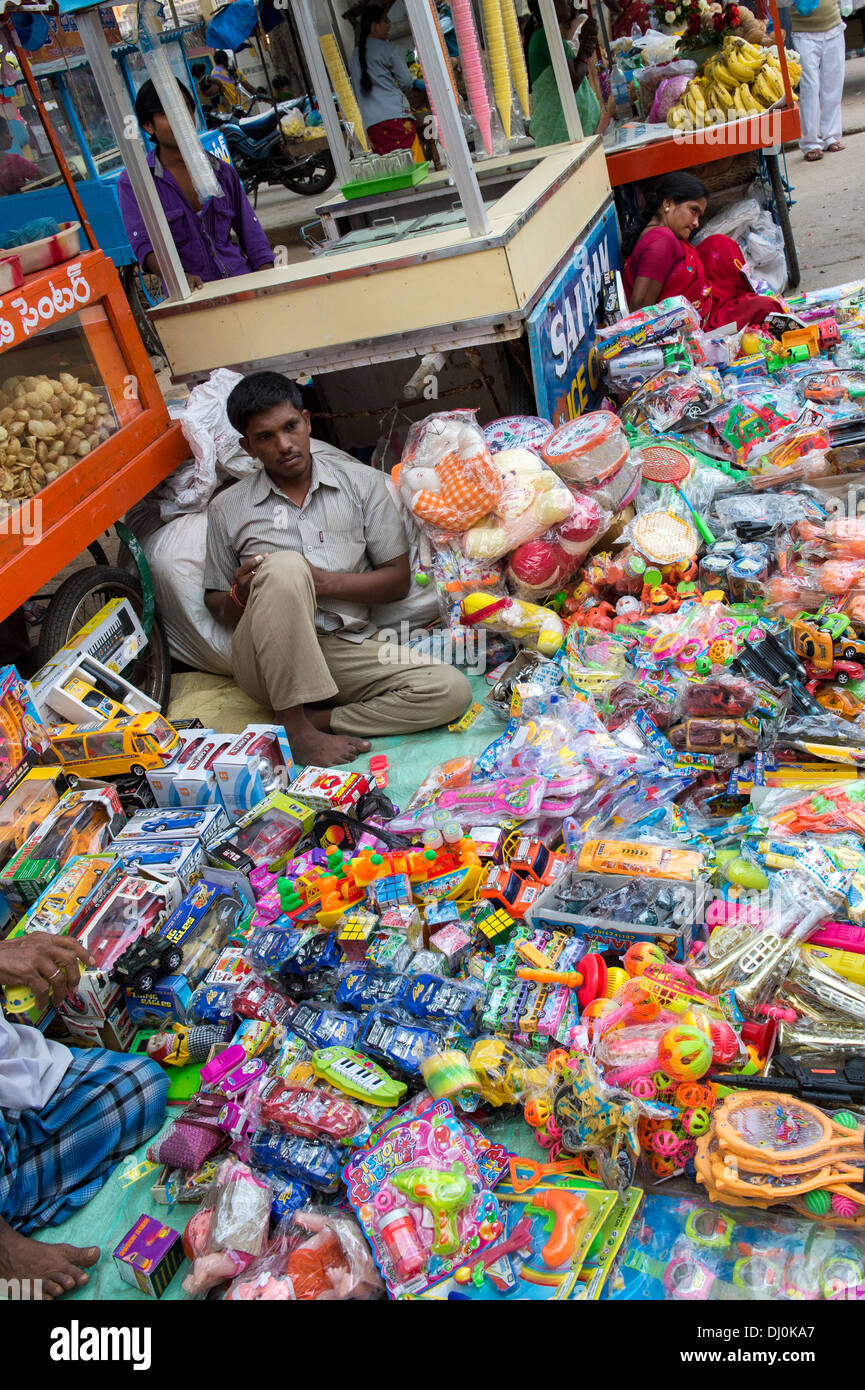 Uomo indiani vendono a buon mercato dei giocattoli di plastica in un mercato indiano. Andhra Pradesh, India Foto Stock