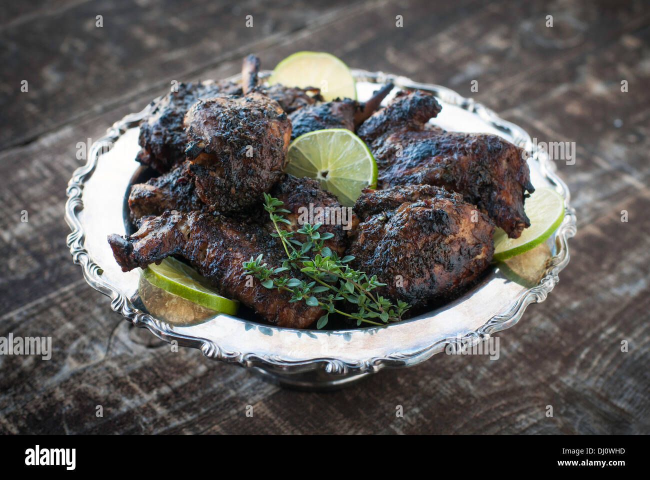 Decorativo piatto d'argento del pollo arrosto con salsa di jerk, calce e guarnire erbe Foto Stock