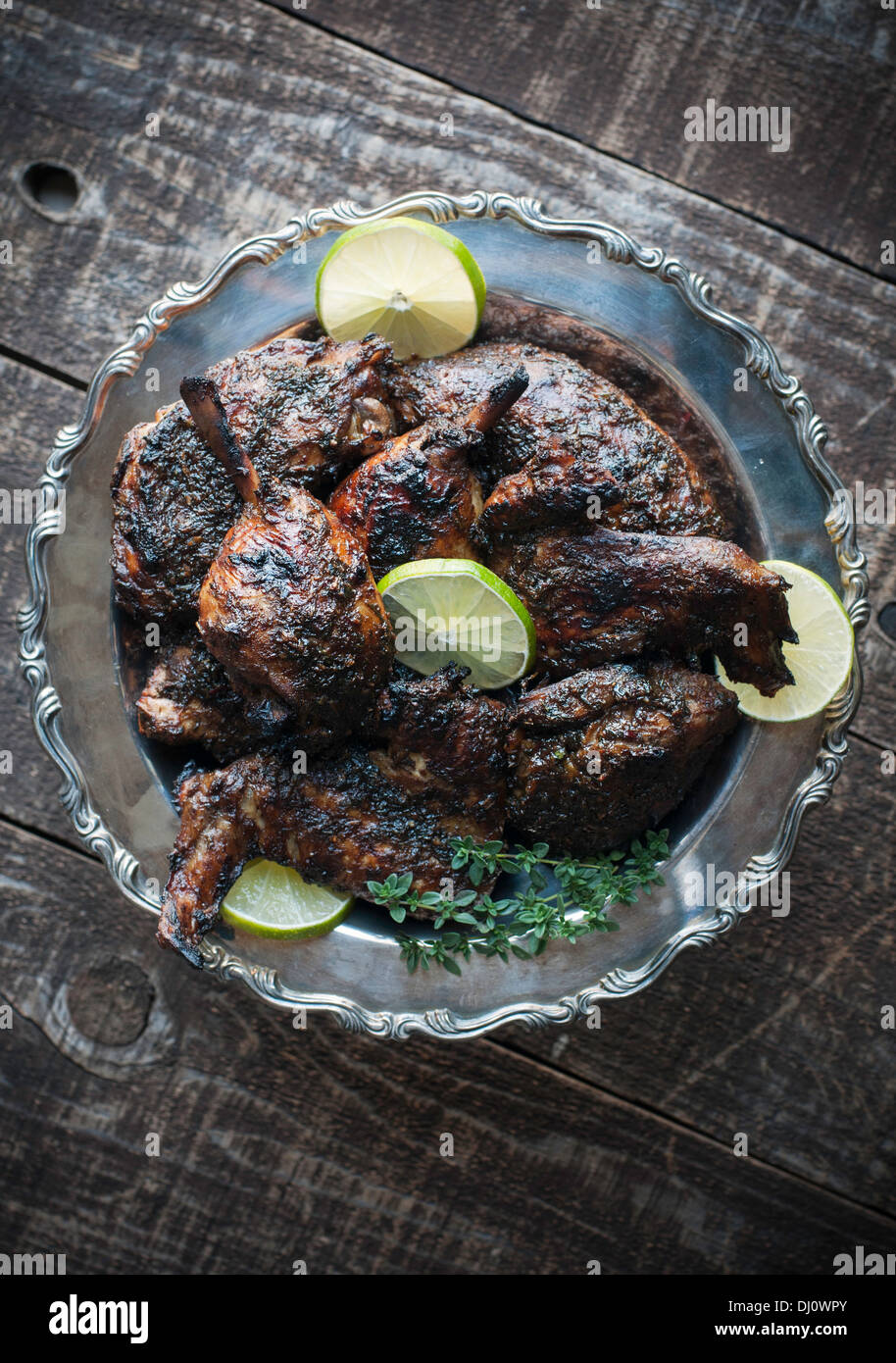 Decorativo piatto d'argento del pollo arrosto con salsa di jerk, calce e guarnire erbe Foto Stock