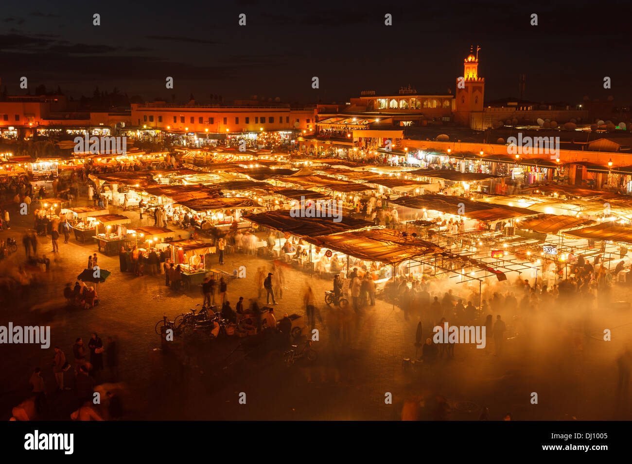 Vista aerea delle grandi città, mercato all'aperto con il minareto della moschea illuminata luminosamente in background di notte a Marrakech in Marocco Foto Stock