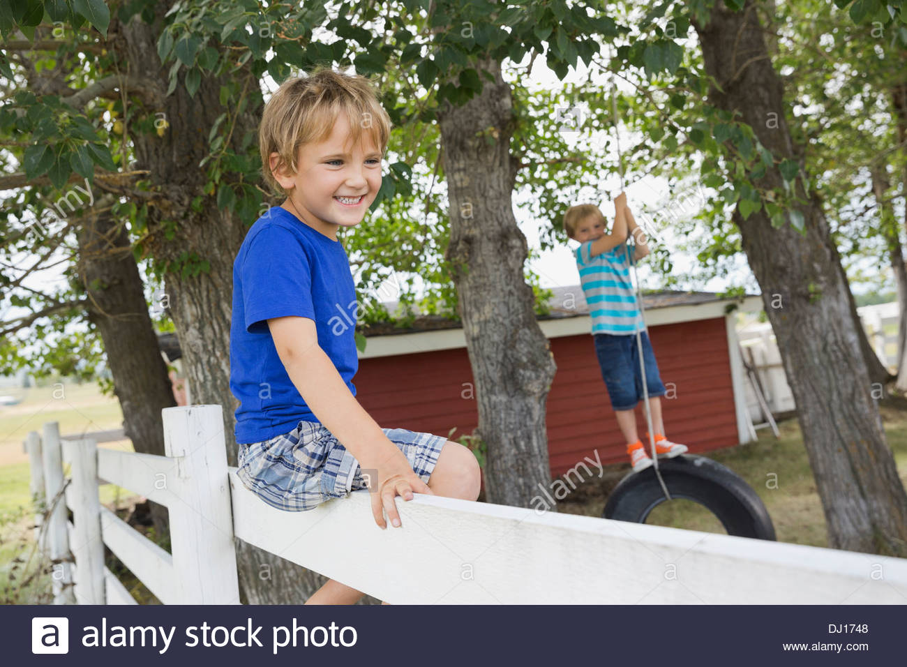 Sorridente Ragazzo seduto sulla recinzione Foto Stock