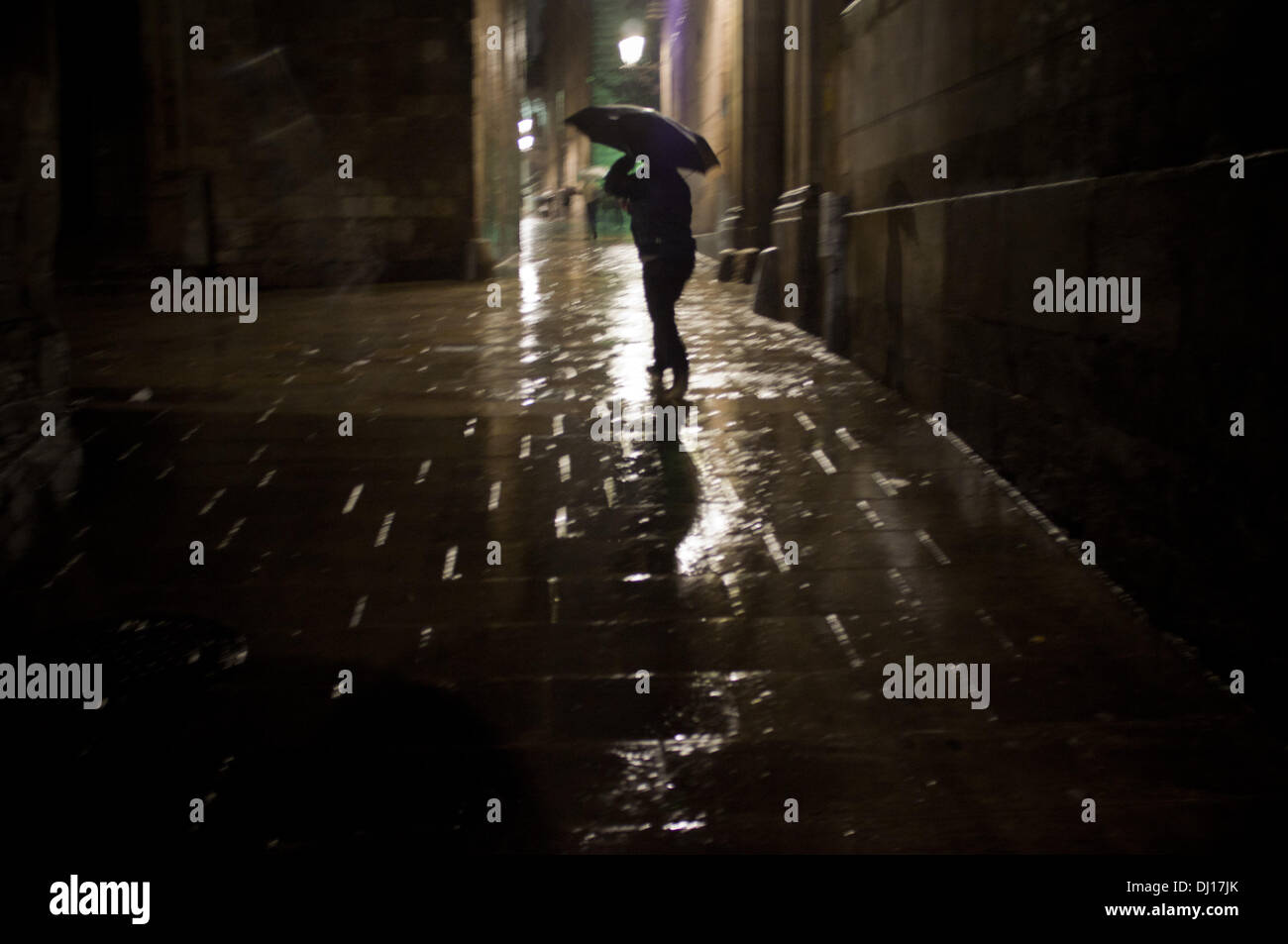 Barcellona Quartiere Gotico, Spagna del xviii Novembre, 2013.Un uomo rifugiarsi sotto un ombrello per le strade di Barcelons Quartiere Gotico. La pioggia persistente su Barcellona dopo mesi senza pioggia. Credito: Jordi Boixareu/Alamy Live News Foto Stock