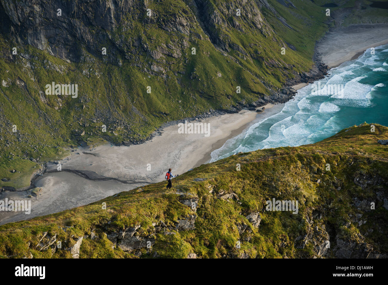 Escursionista femmina affacciato sulla spiaggia Kvalvika dalla montagna vicina, Moskenesoy, Isole Lofoten in Norvegia Foto Stock