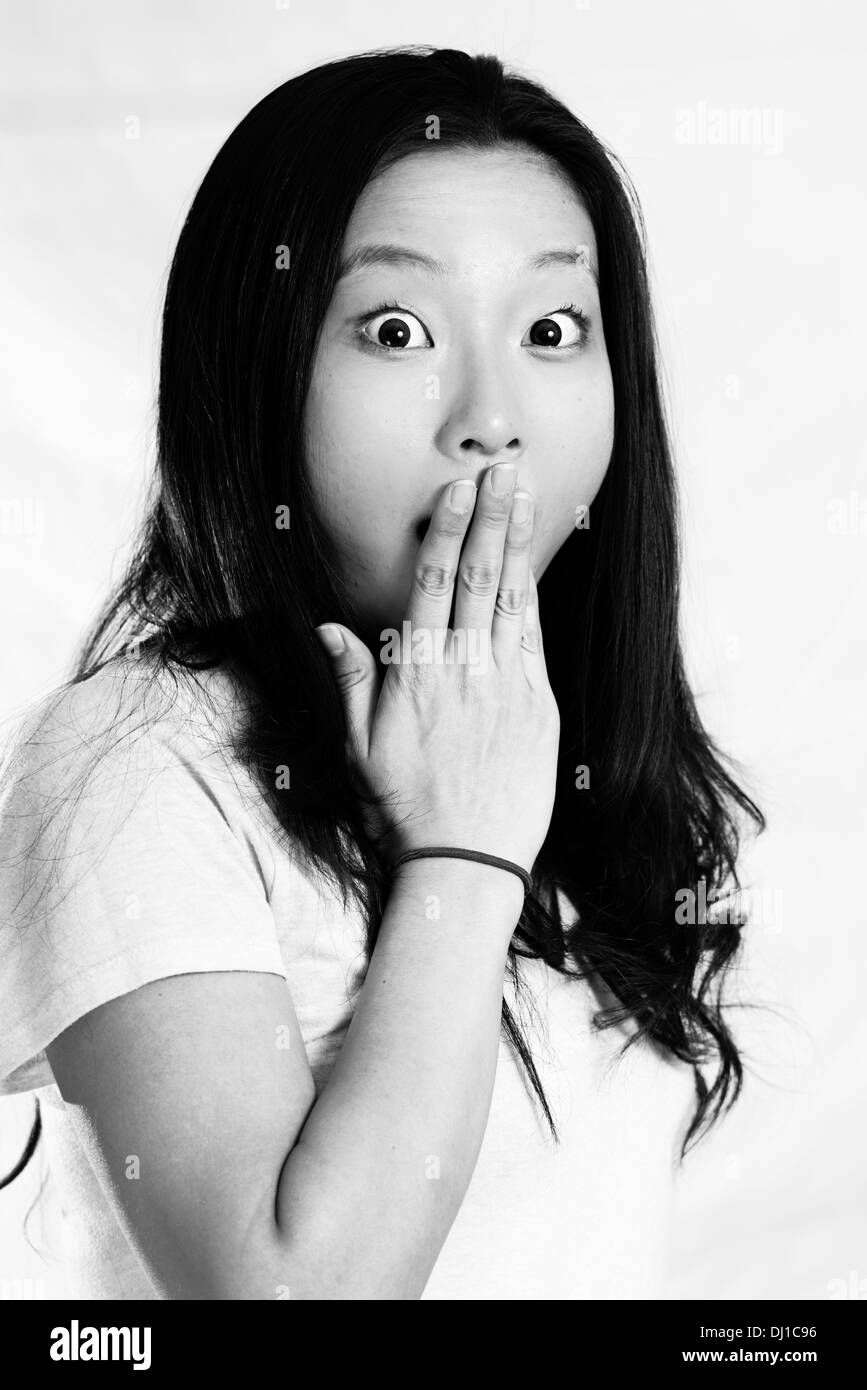 Ritratto di giovane donna guardando scioccato e coprendo la sua bocca in bianco e nero style Foto Stock