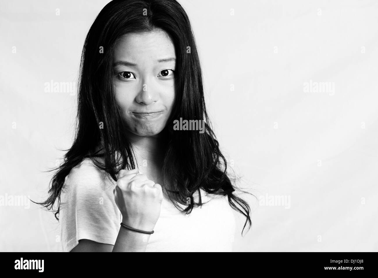 Ritratto di attraente giovane donna clenching il suo pugno di incoraggiamento, in bianco e nero style Foto Stock