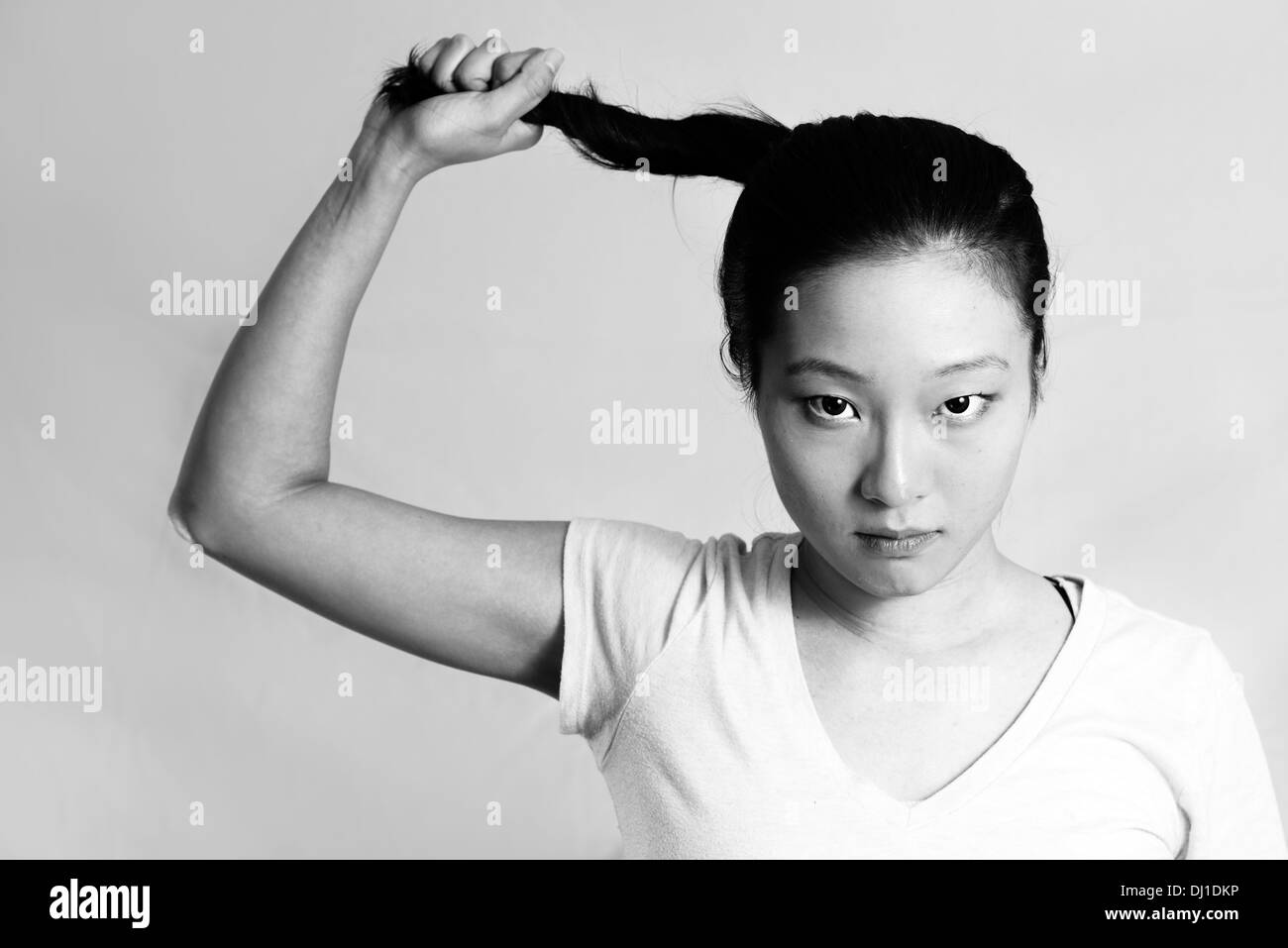 Ritratto di lonely giovane donna tirando i suoi capelli cercando frustrati, in bianco e nero style Foto Stock
