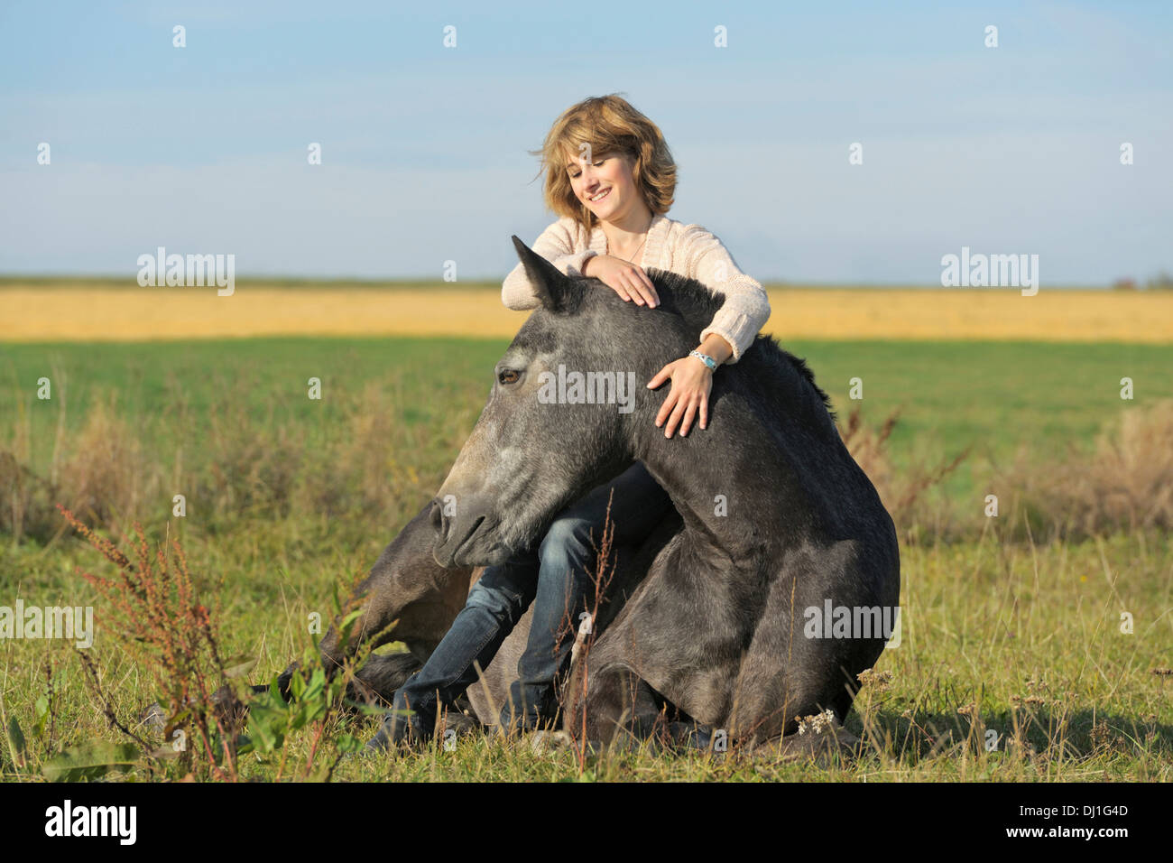 Giovane donna indietro il suo pony Connemara che è giacente pascolo forte fiducia tra cavallo Cavaliere Foto Stock