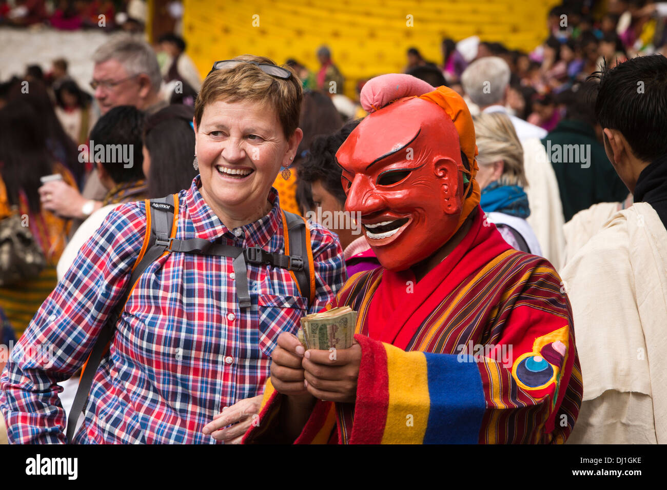 Il Bhutan, Thimpu Dzong, annuale Tsechu femmina turista occidentale con atsara clown ballerina azienda soldi in mano Foto Stock