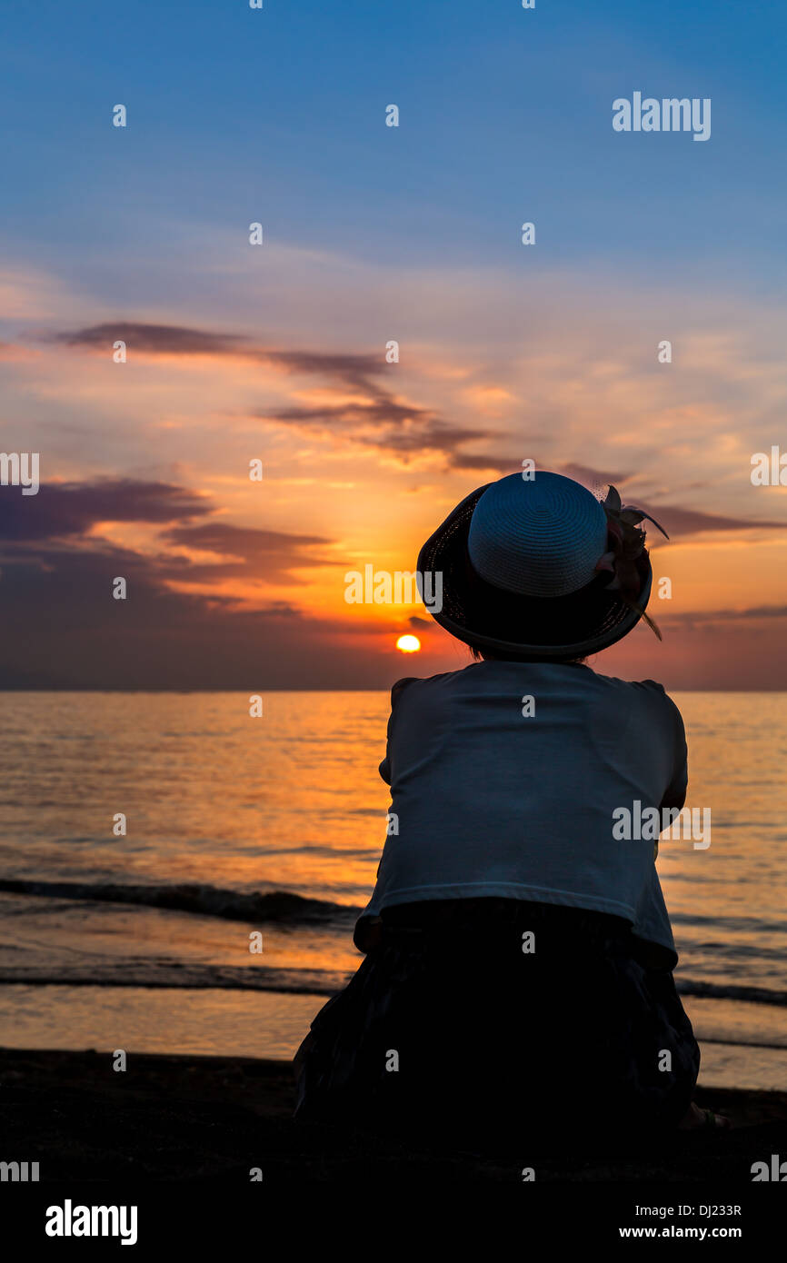 Donna di guardare il tramonto, Lovina Beach, Bali, Indonesia Foto Stock