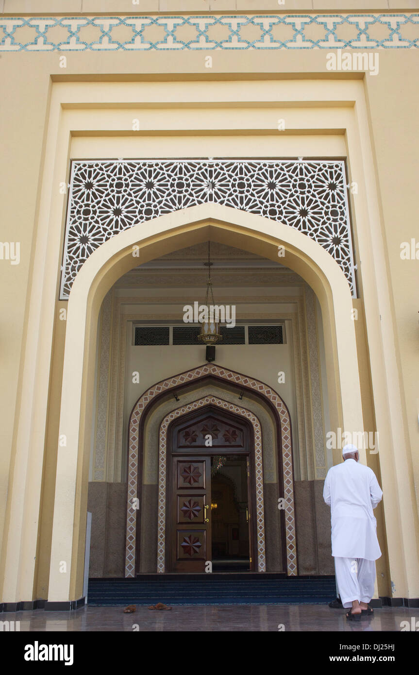 Un uomo musulmano si prepara ad entrare in un Abu Dhabi moschea negli Emirati Arabi Uniti dopo la preghiera chiamata Foto Stock