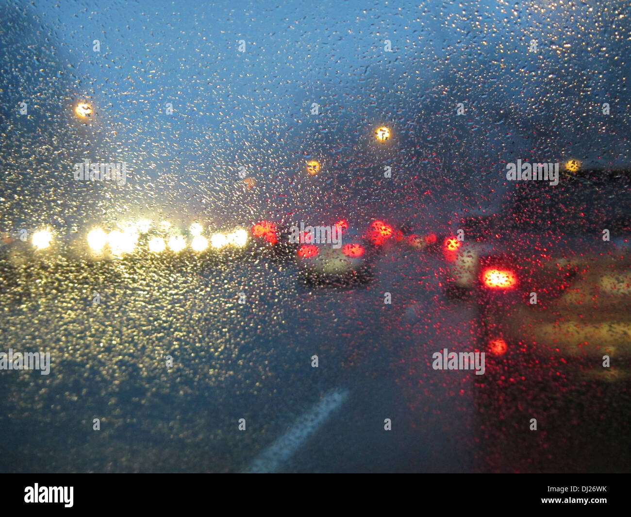 La guida su una strada al crepuscolo in ora di punta con pioggia e nebbia raccolta sul parabrezza. Foto Stock