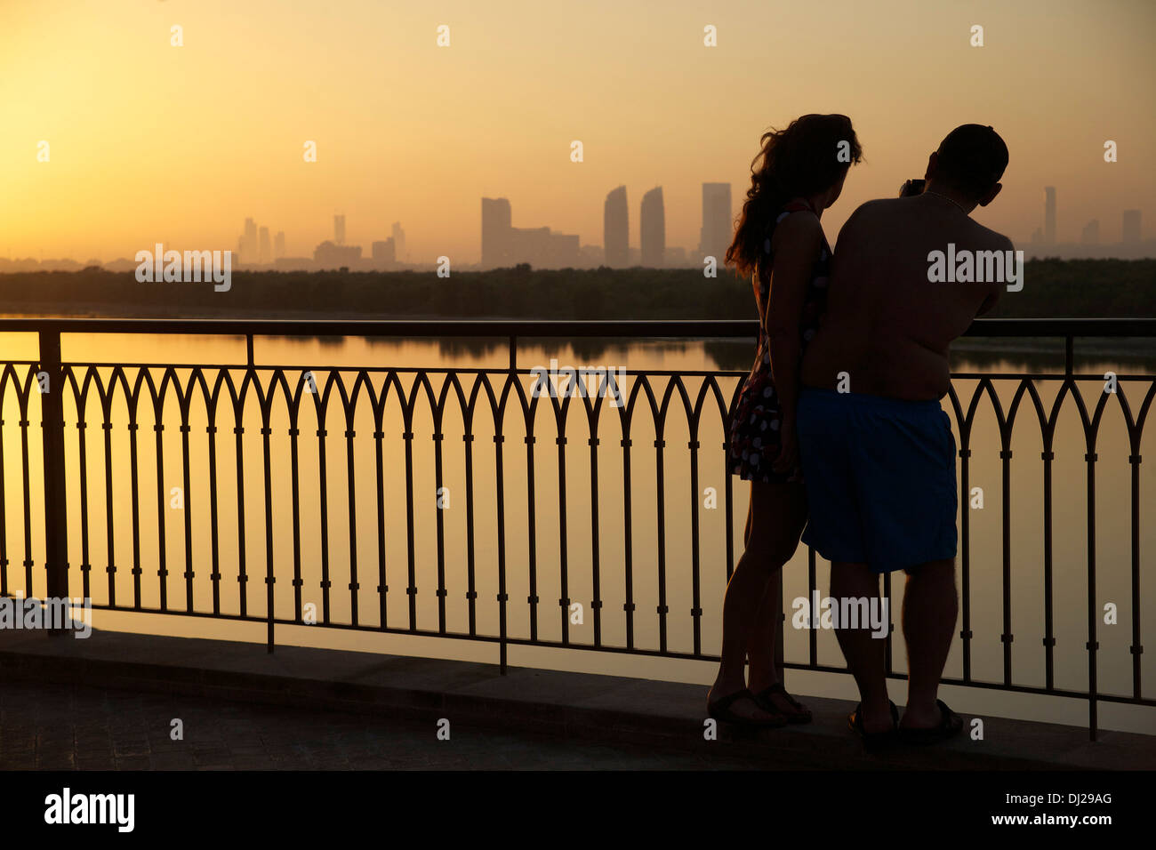 Un paio di fotografare il tramonto skyline di Abu Dhabi attraverso le Mangrovie orientale Foto Stock