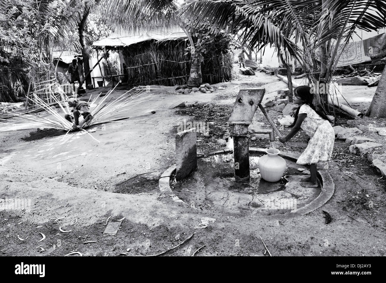 Ragazza indiana di riempimento acqua in plastica vaso da un villaggio rurale la pompa a mano. Andhra Pradesh, India. In bianco e nero. Foto Stock