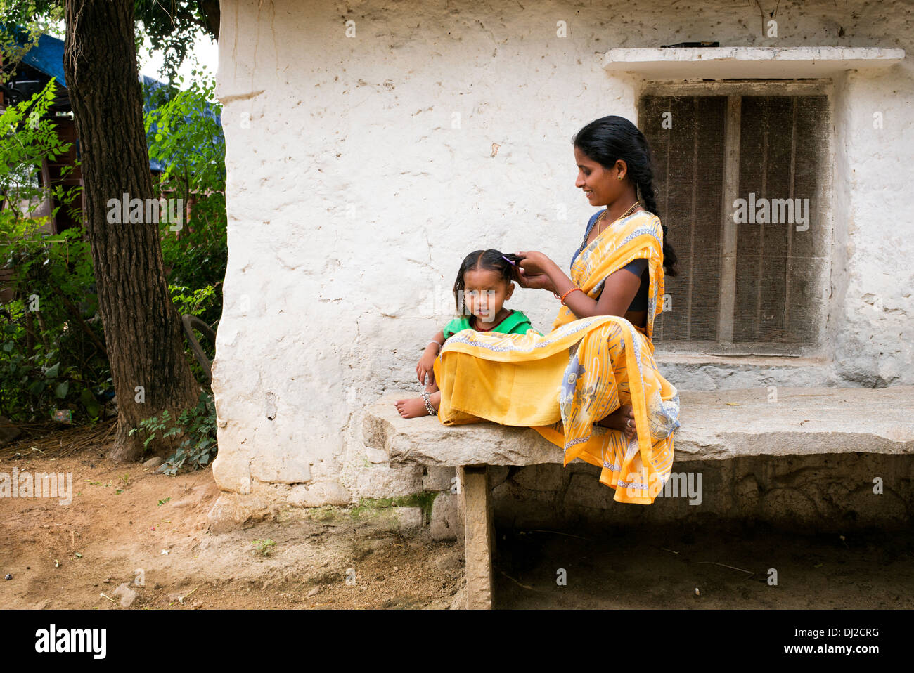 Madre indiana la sua pettinatura giovani figlie i capelli in una zona rurale villaggio indiano. Andhra Pradesh, India Foto Stock
