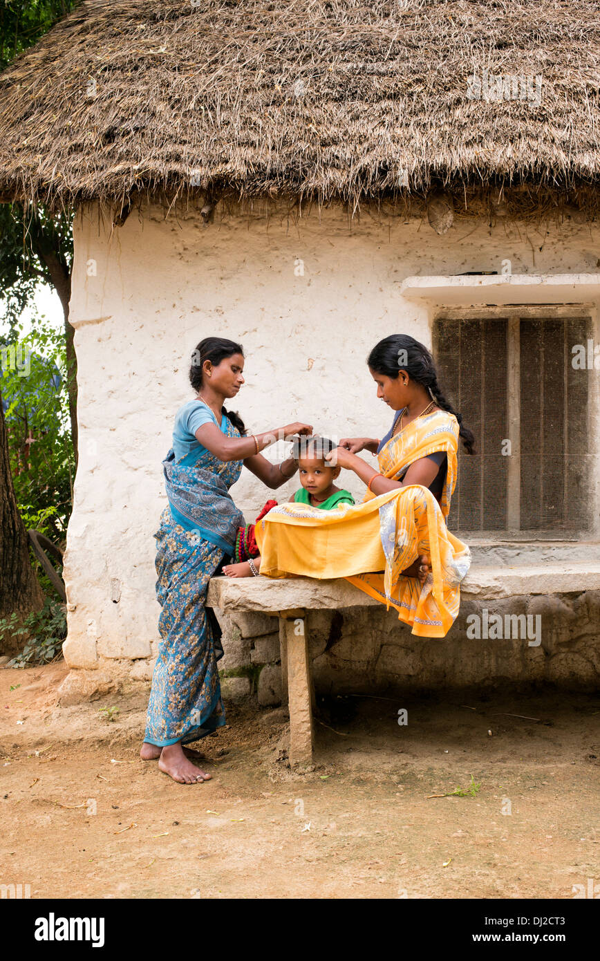 Madre indiana e pettinare i suoi giovani figlie i capelli in una zona rurale villaggio indiano. Andhra Pradesh, India Foto Stock