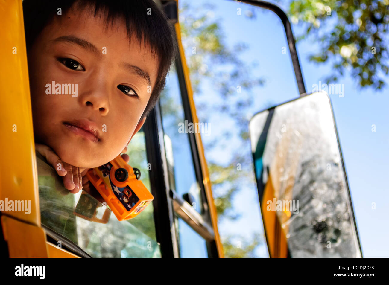 Giovane, dolce, ragazzo bhutanesi sbirciando attraverso la finestra del bus Foto Stock
