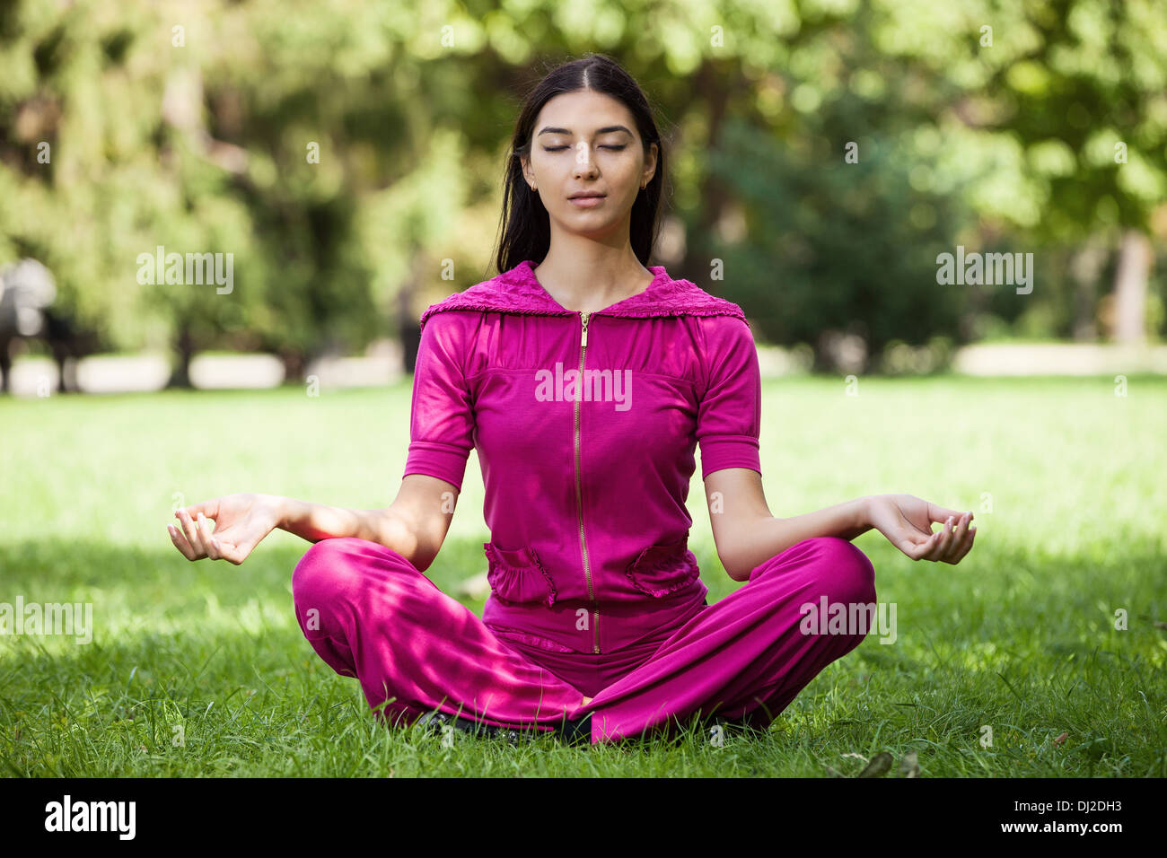 Bella ragazza giovane meditando seduto su erba nel parco Foto Stock