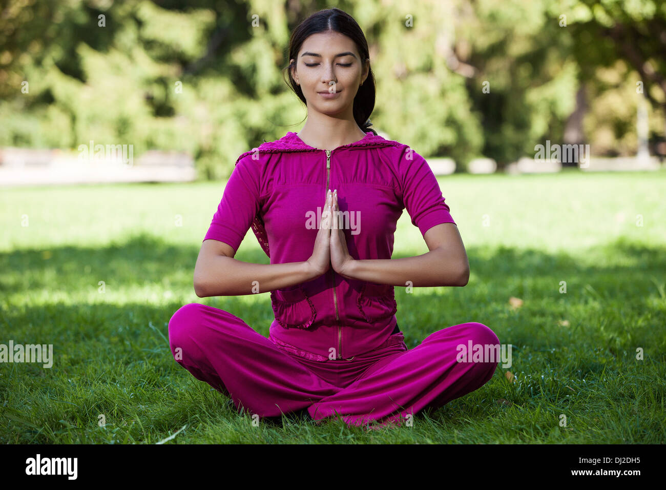 Bella ragazza giovane donna meditando mentre è seduto sull'erba Foto Stock