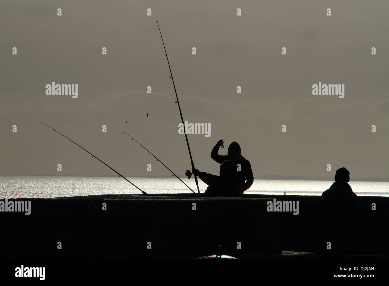 Gli uomini la pesca sulla parete del porto. Foto Stock