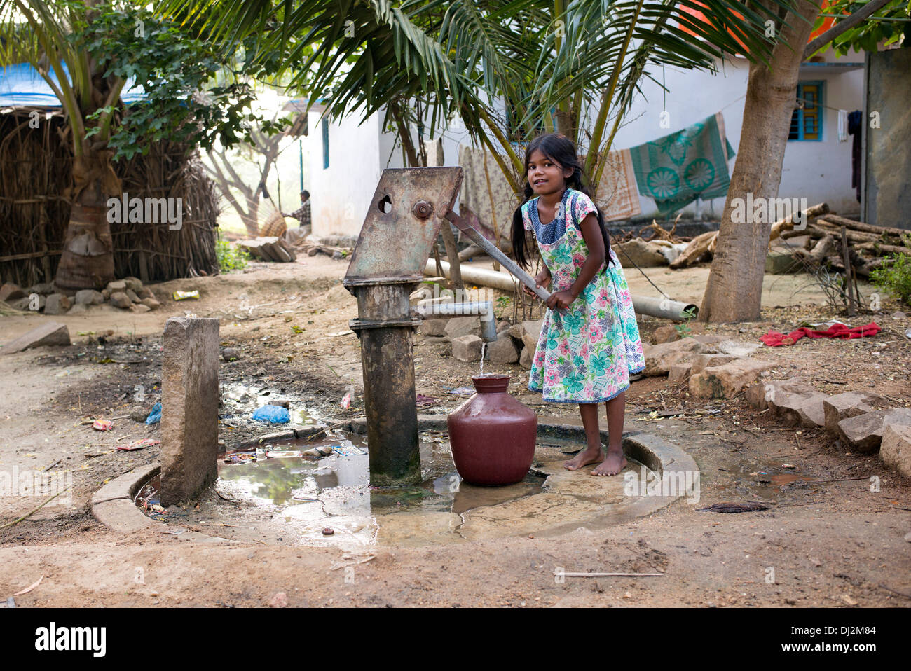 Ragazza indiana di riempimento acqua in plastica vaso da un villaggio rurale la pompa a mano. Andhra Pradesh, India Foto Stock