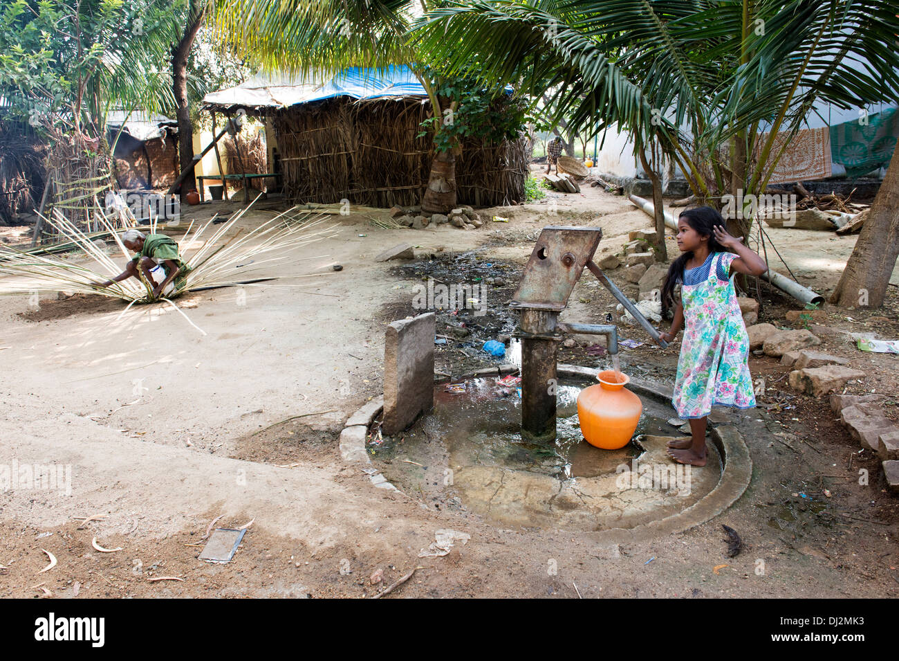 Ragazza indiana di riempimento acqua in plastica vaso da un villaggio rurale la pompa a mano. Andhra Pradesh, India Foto Stock