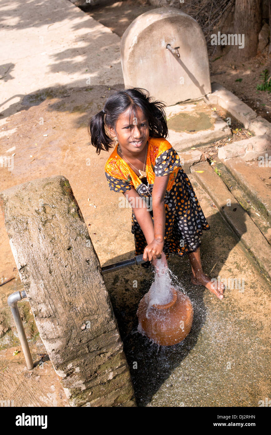 Ragazza indiana il riempimento di un contenitore di plastica con acqua da un tubo montante in un territorio rurale villaggio indiano. Andhra Pradesh, India Foto Stock