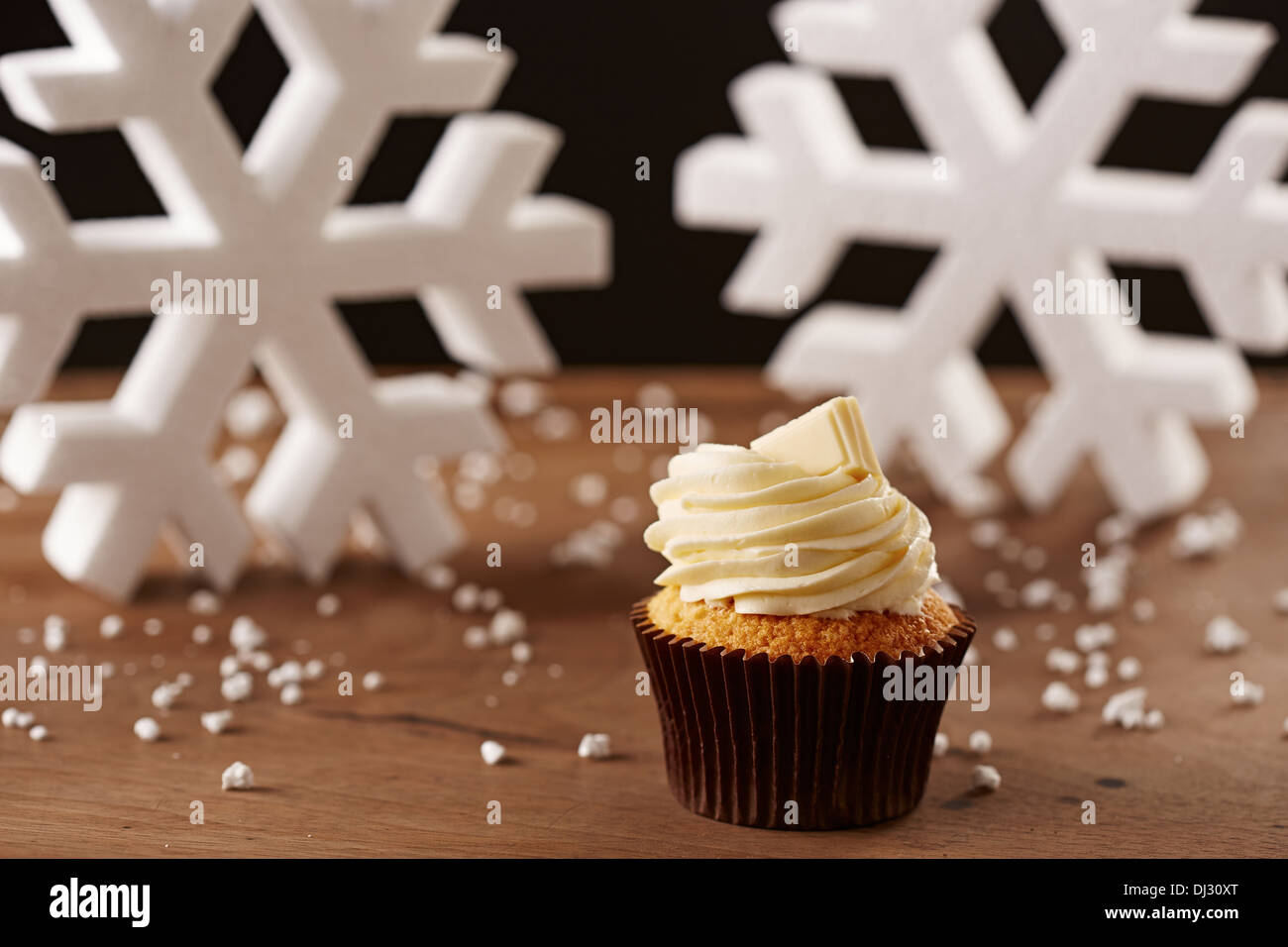 Il cioccolato bianco cupcake su bianco fiocchi di neve sullo sfondo di Natale Foto Stock