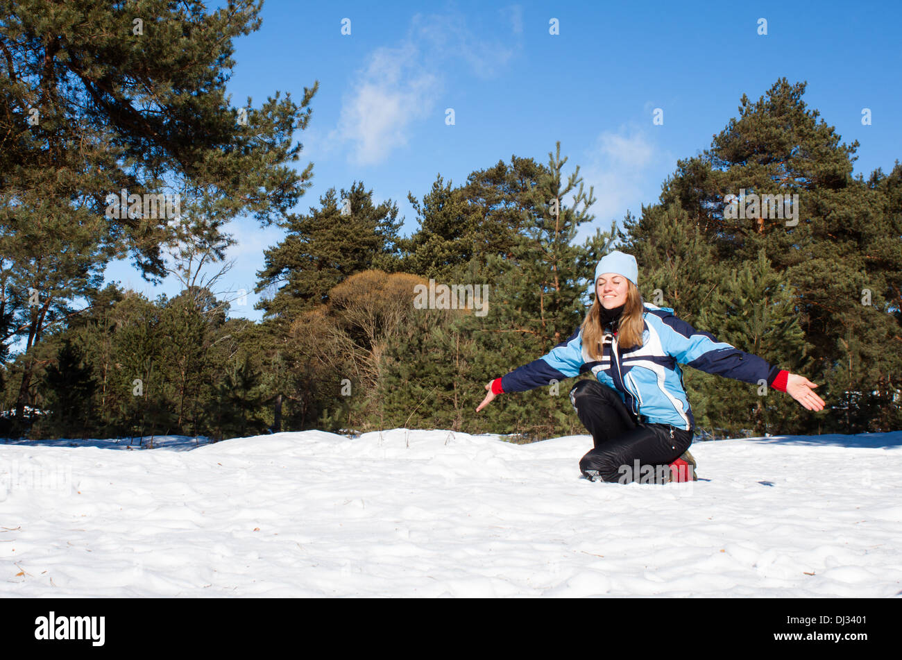Donna seduta bianco della neve pineta giornata di sole " chiuso " Occhi sorridenti "scena d'inverno" Foto Stock
