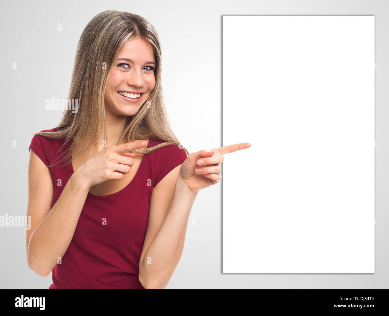 Allegro giovane donna che mostra un cartello bianco con le mani Foto Stock