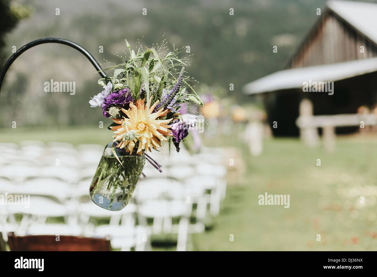 Un vaso di fiori selvatici impiccagione per il decoro ad un esterno di cerimonia nuziale; Pemberton, British Columbia, Canada Foto Stock