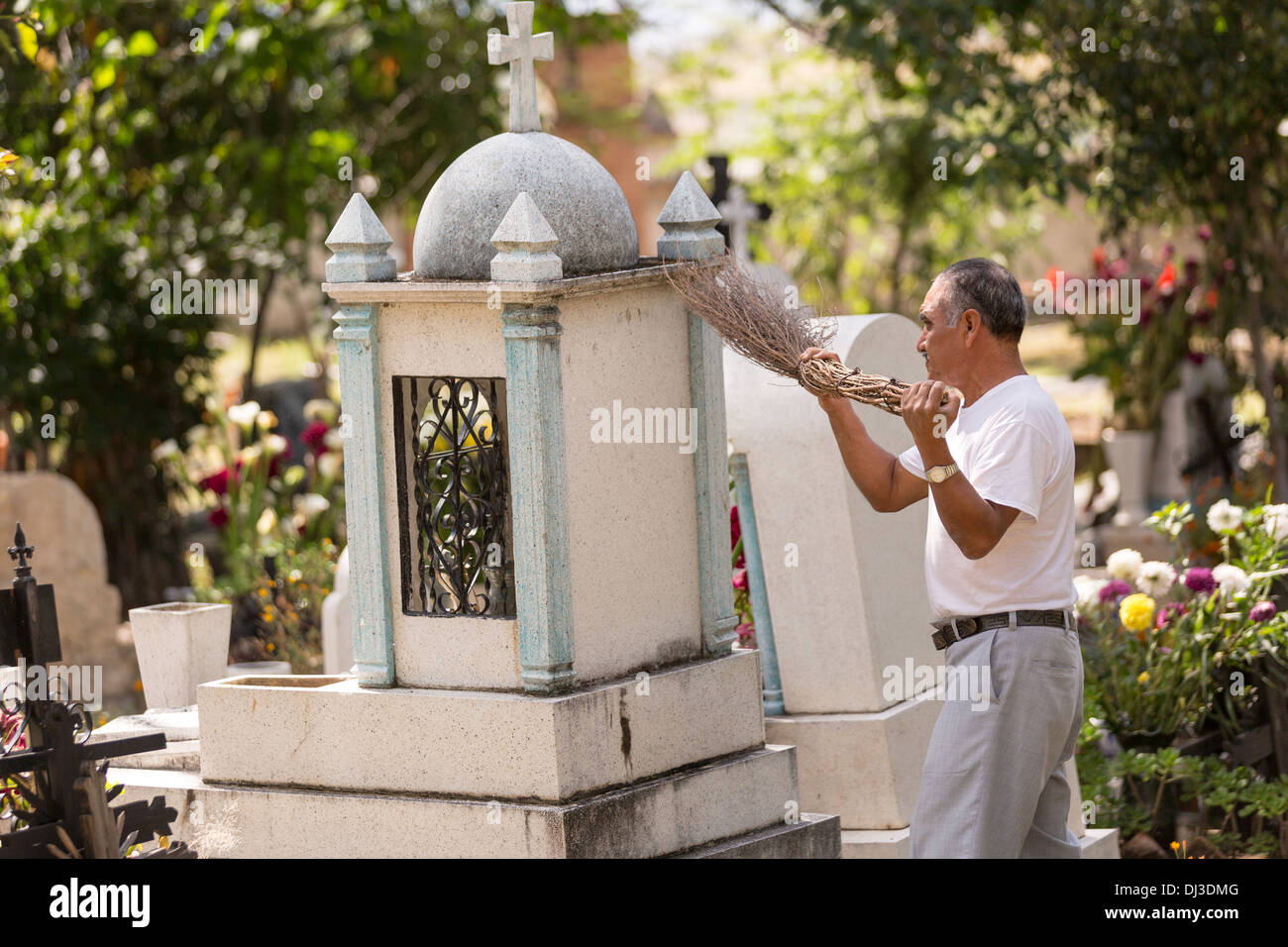 Un uomo anziano luoghi pulisce la tomba di un membro della famiglia all'inizio del Giorno dei Morti festival in Teotitlan, Messico. Foto Stock
