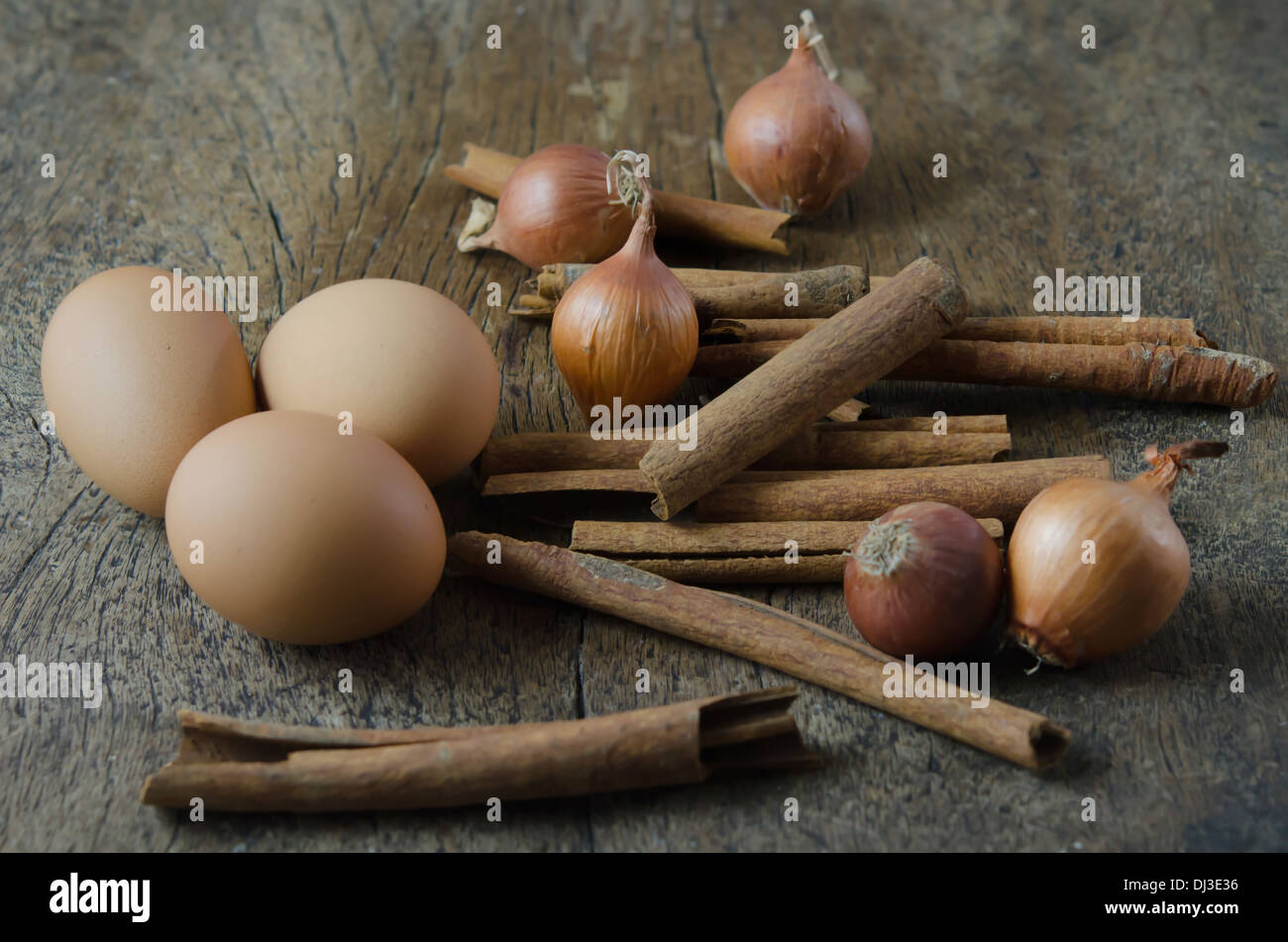 Uova, bastoncini di cannella e la cipolla su sfondo di legno Foto Stock