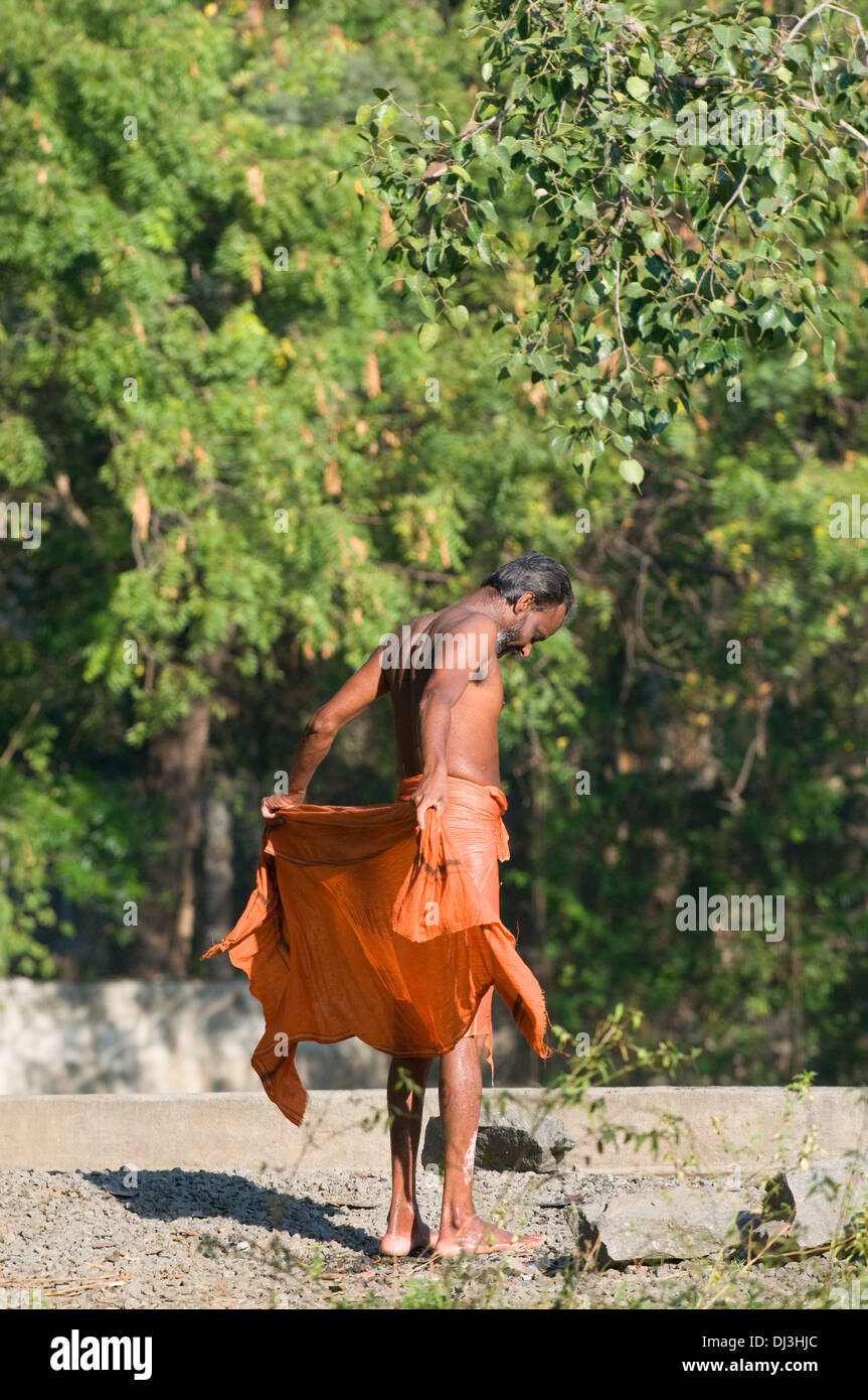 Sadhu, Indiana uomo santo, essiccamento se stesso e il suo dhothi e camicia dopo la balneazione in locali del serbatoio di lavaggio a Tiruvannamalai Foto Stock
