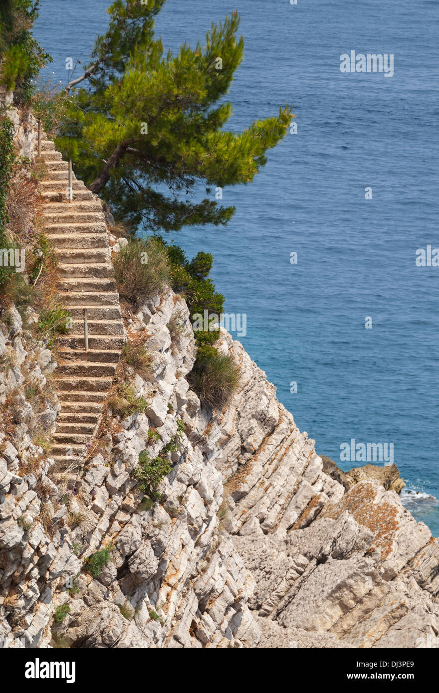 Vecchie scale di pietra va giù sulla roccia per l'acqua di mare. Mare Adriatico, Montenegro Foto Stock
