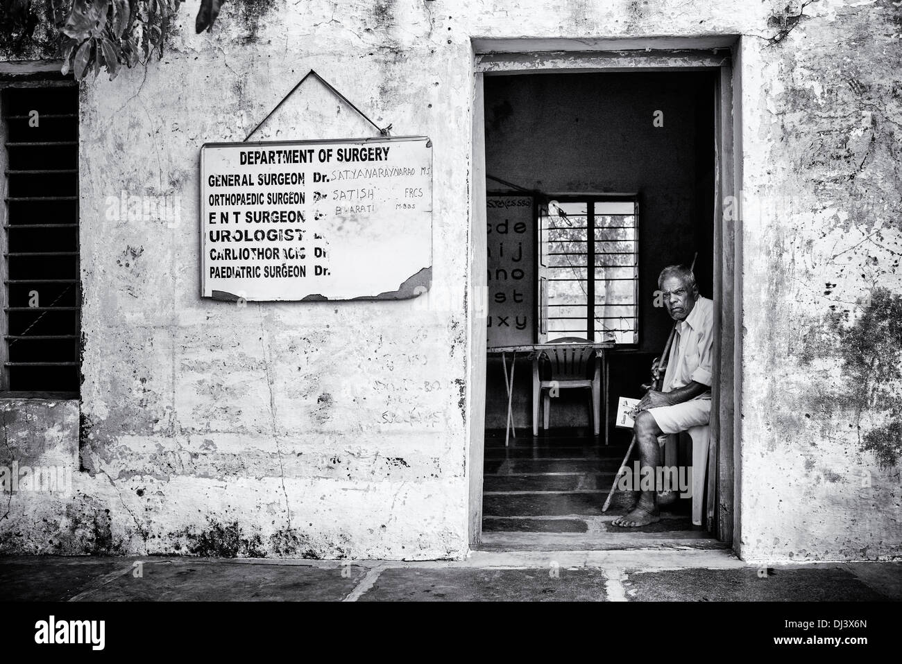 Indiana rurale uomo seduto nella clinica di chirurgia presso Sri Sathya Sai Baba mobile ospedale outreach. Andhra Pradesh, India. Monocromatico Foto Stock