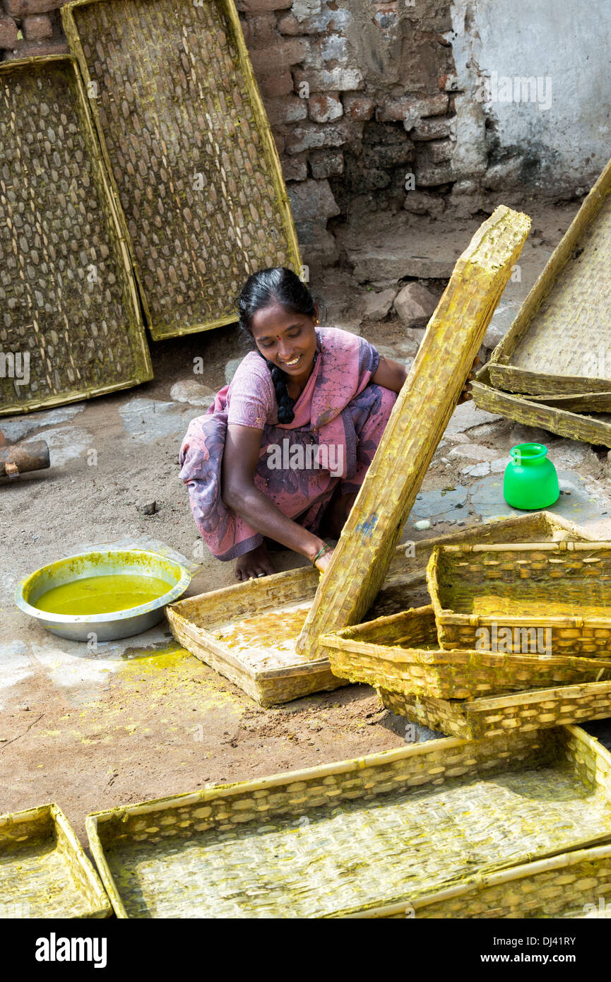 Donna indiana utilizzando curcuma acqua come un disinfettante per pulire i vassoi del baco da seta in un villaggio rurale. Andhra Pradesh, India Foto Stock