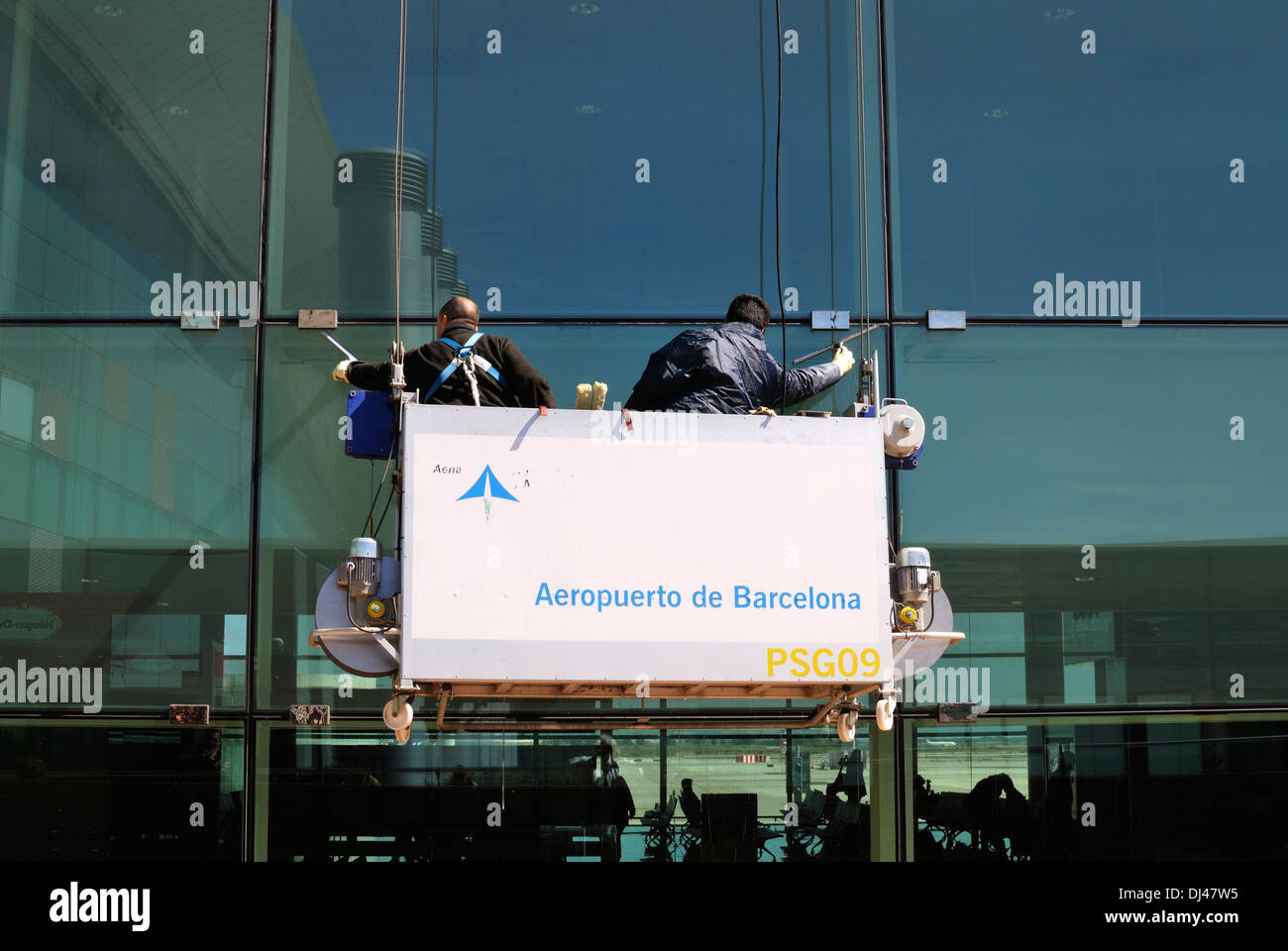 Due operai nel paranco di pulizia su windows terminal dell aeroporto. Barcellona. La Catalogna. Spagna Foto Stock