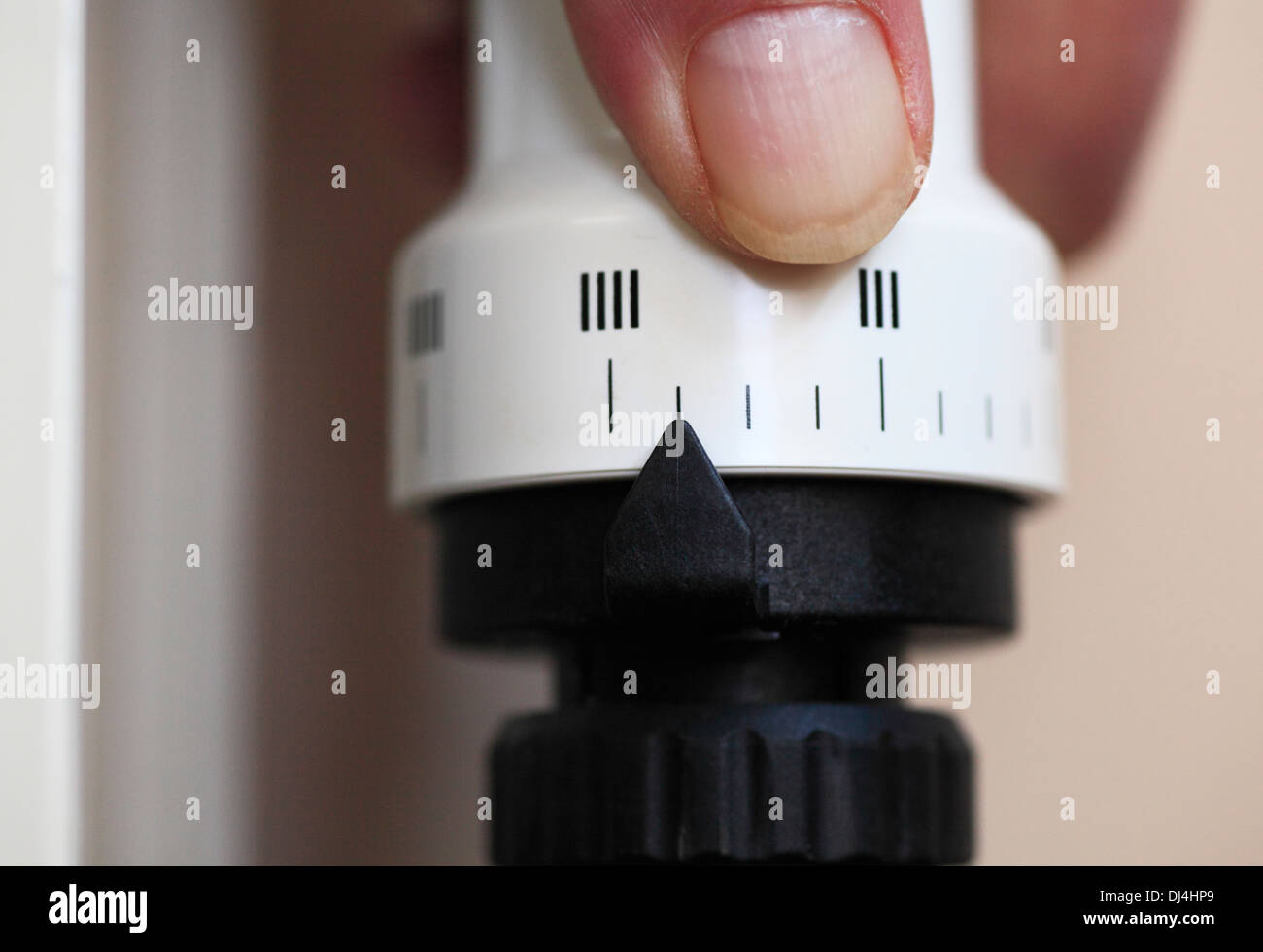 Mano d'uomo la regolazione di una valvola termostatica sul radiatore a casa. Foto Stock