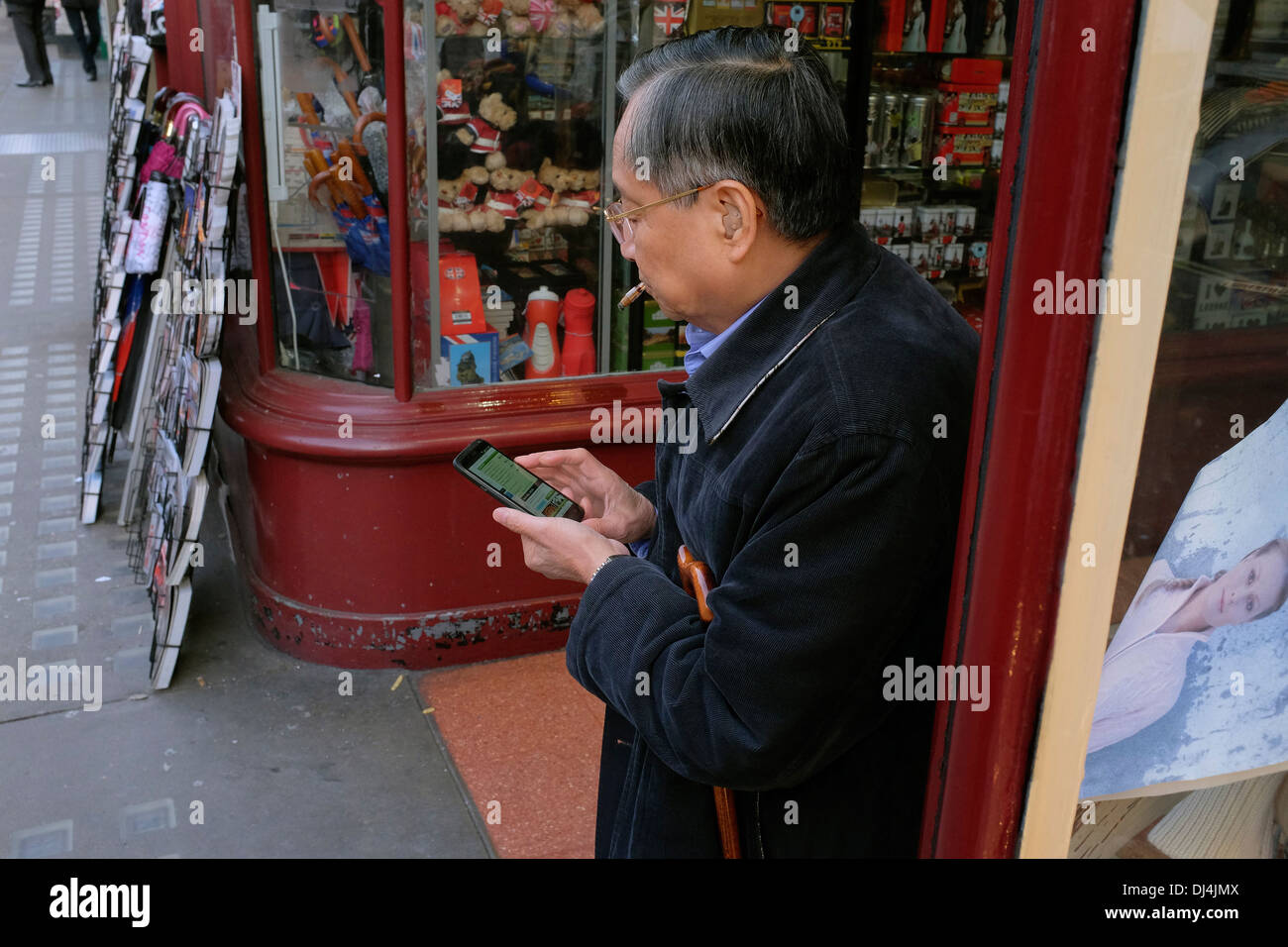 Anziani uomo cinese utilizza lo smartphone, Piccadilly, Londra, Regno Unito Foto Stock