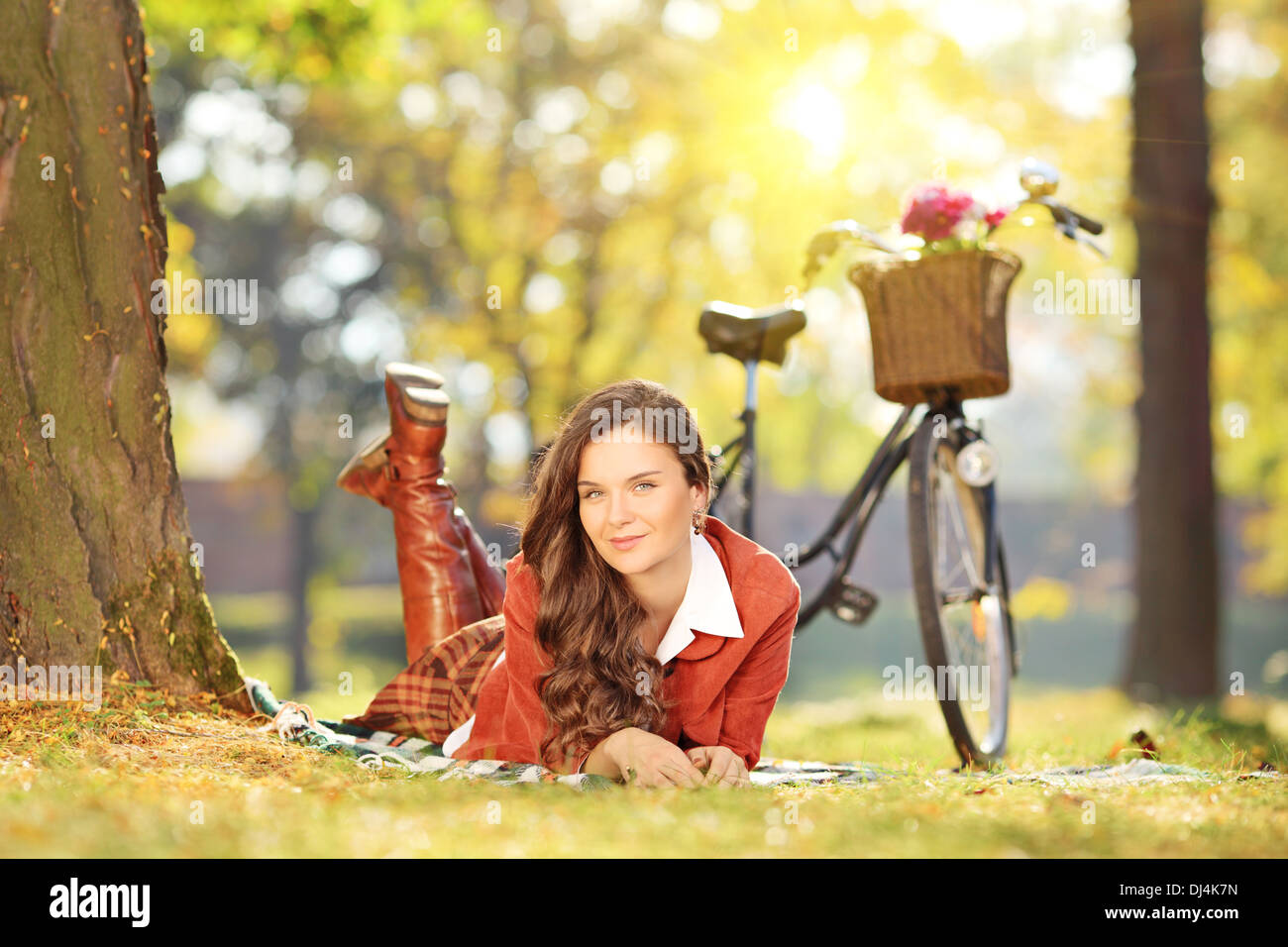 Giovani femmine sdraiati su un prato con bicicletta in un parco in una giornata di sole Foto Stock