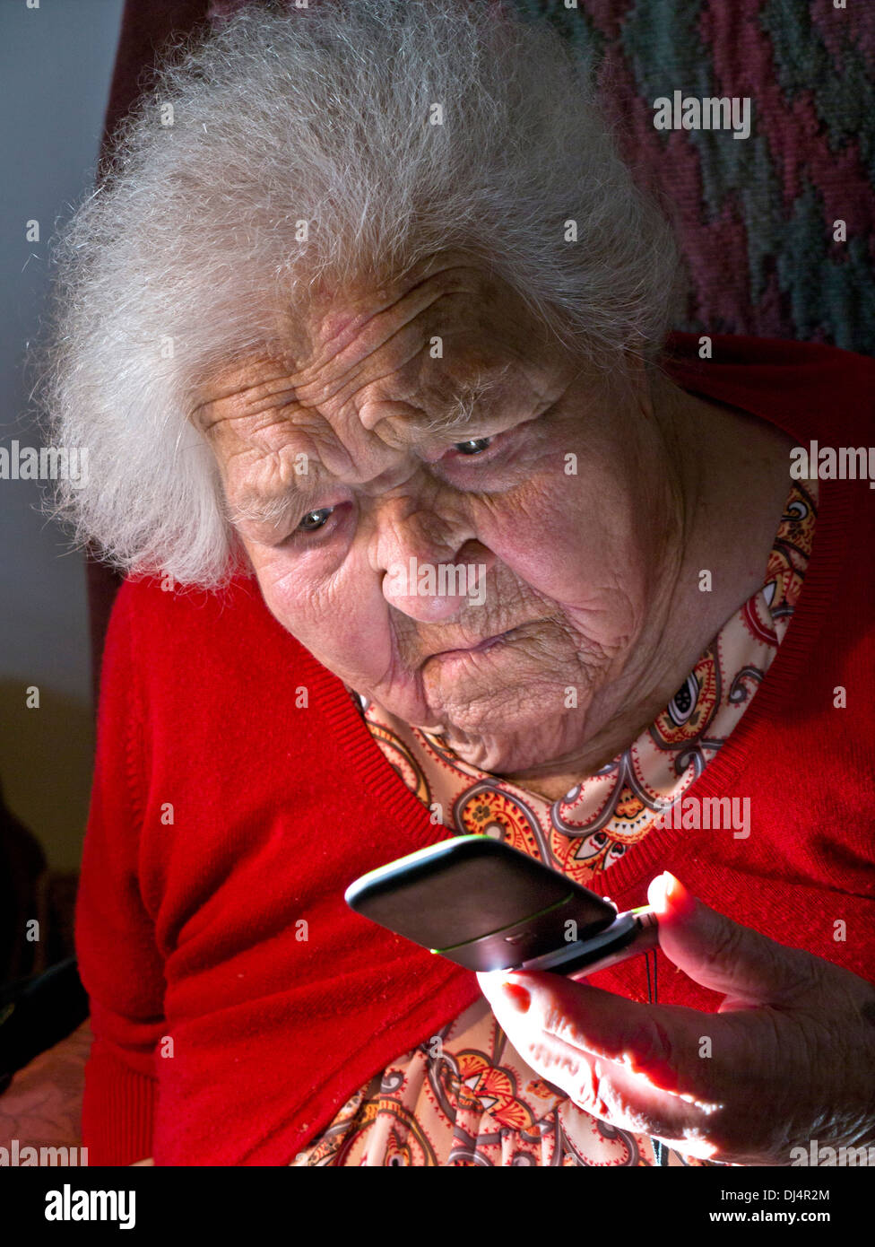 Malinconici anziana signora imparando a usare il suo flip aperto telefono mobile Foto Stock