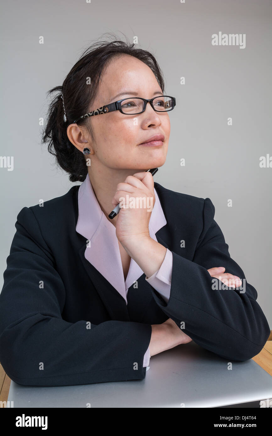 Professional woman in business suit con un computer portatile chiuso sulla scrivania Foto Stock